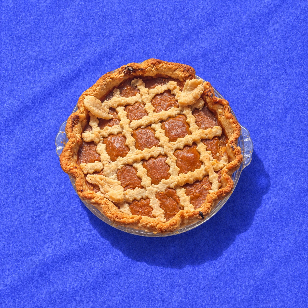 A full-sized pumpkin pie on vivid blue fabric